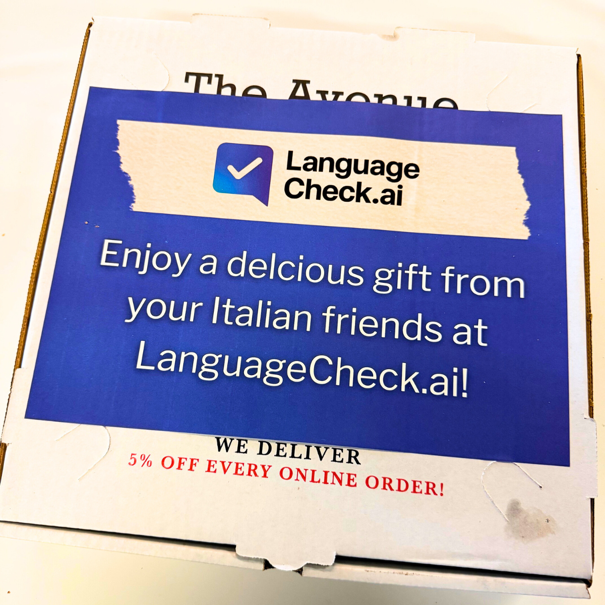 Enjoy a delcious gift from your Italian friends at LanguageCheck.ai advertising campaign on pizza box with small typo